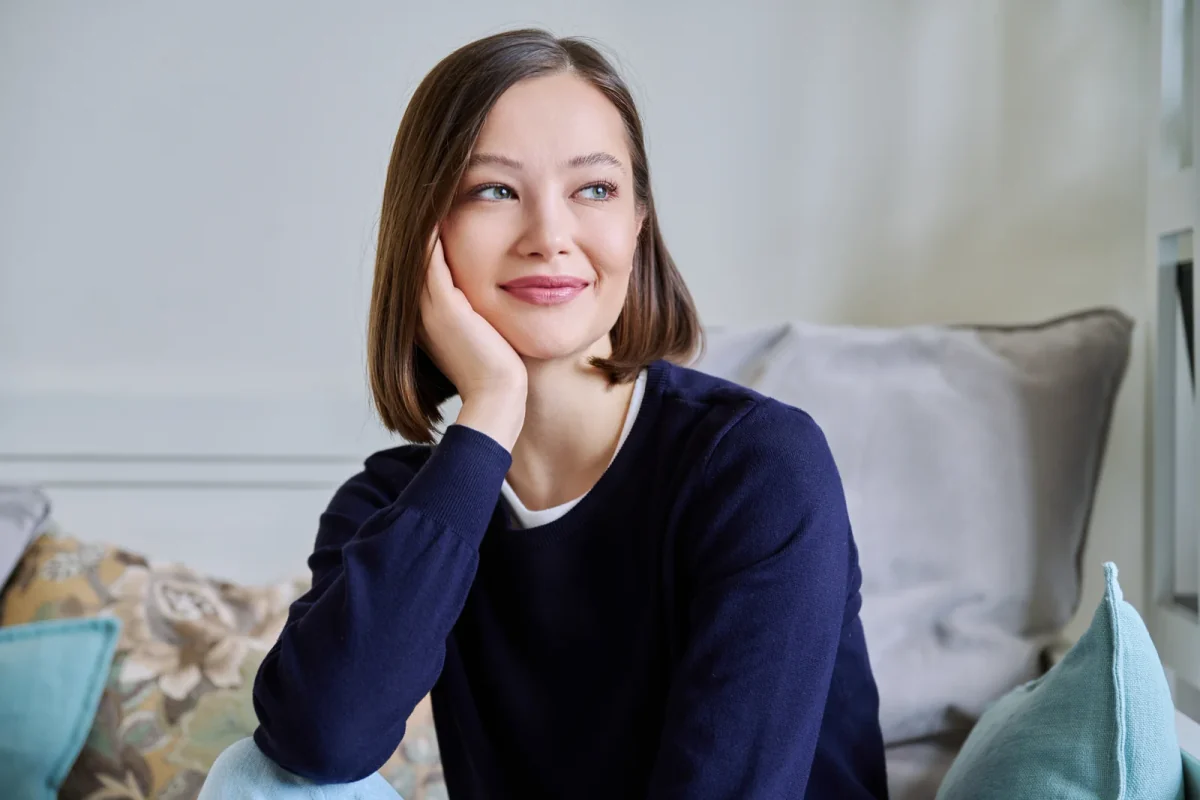 Woman in a navy sweater resting her cheek on her hand